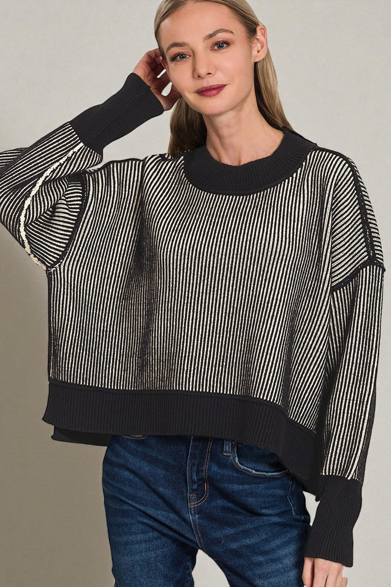 Woman wearing a black and white striped sweater with a plain background