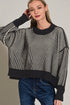Woman wearing a black and white striped sweater with a plain background