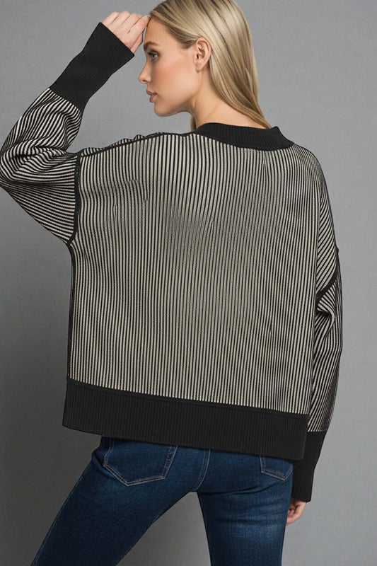 Woman wearing a black and white striped sweater with a gray background