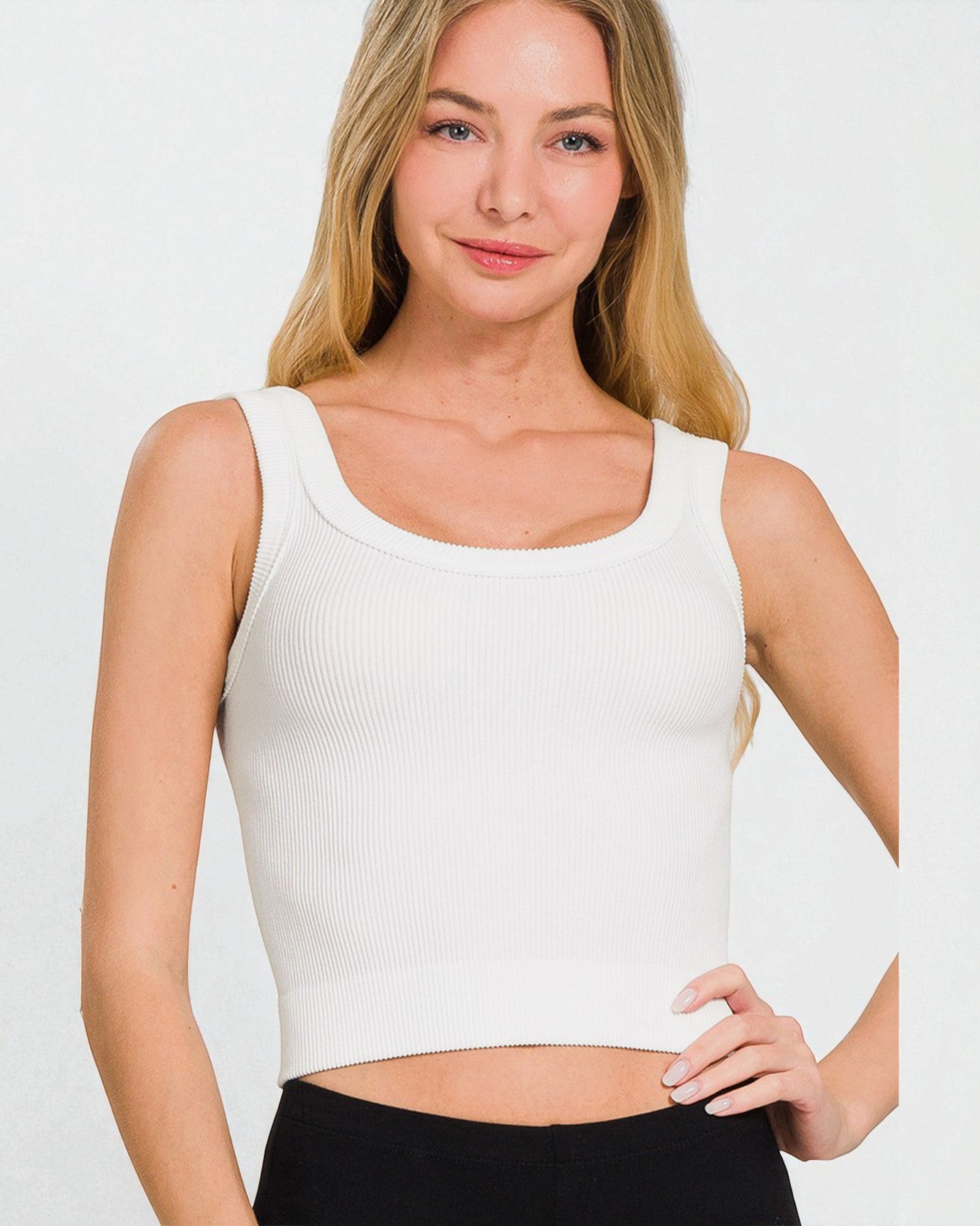 Woman wearing a white tank top against a plain background