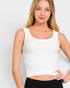 Woman wearing a white sleeveless top against a plain background