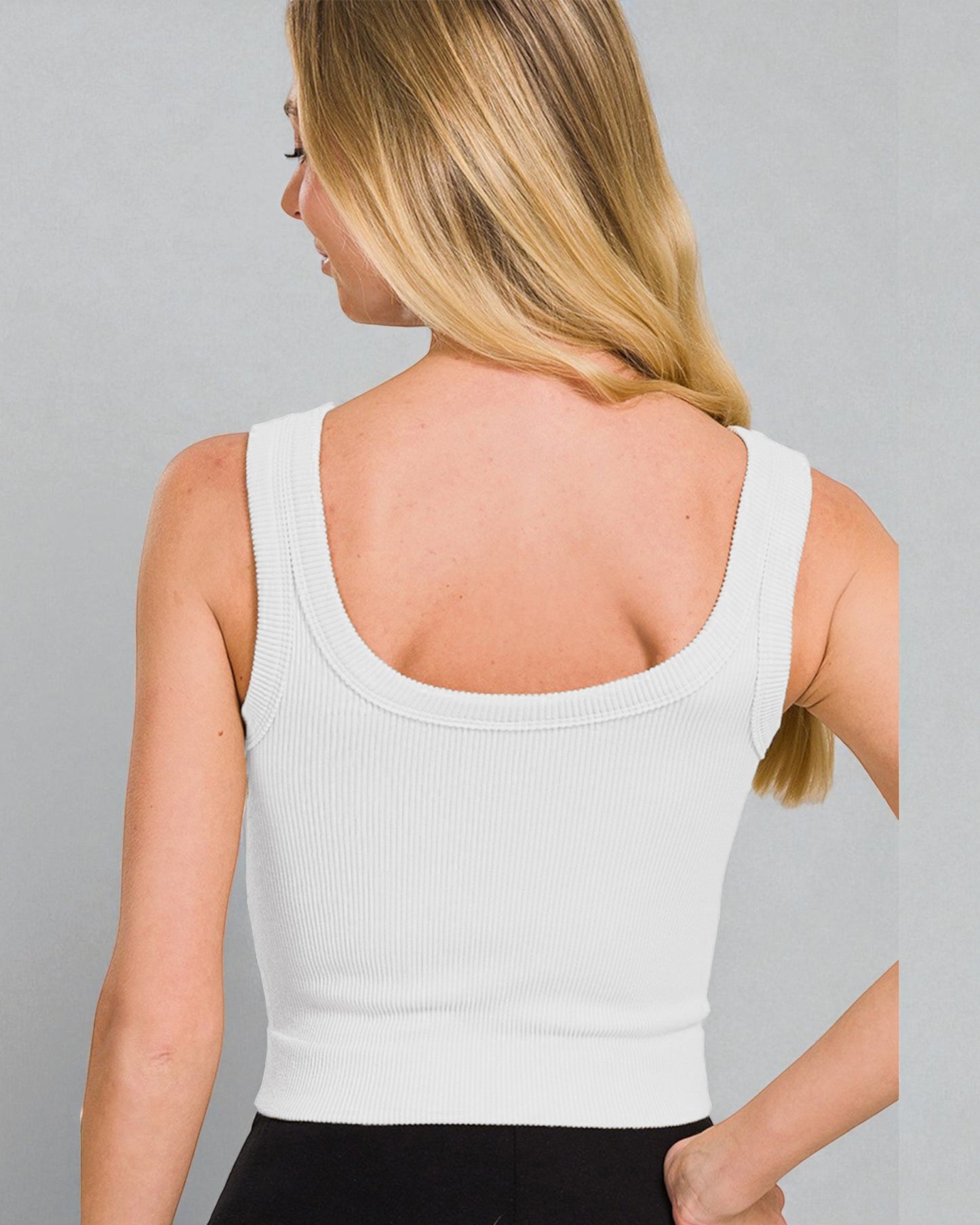 Woman wearing a white tank top against a gray background