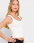 Woman wearing a white tank top against a plain background