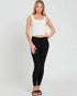Woman wearing a white sleeveless top and black leggings on a plain background