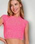 Woman wearing a pink crop top against a plain background