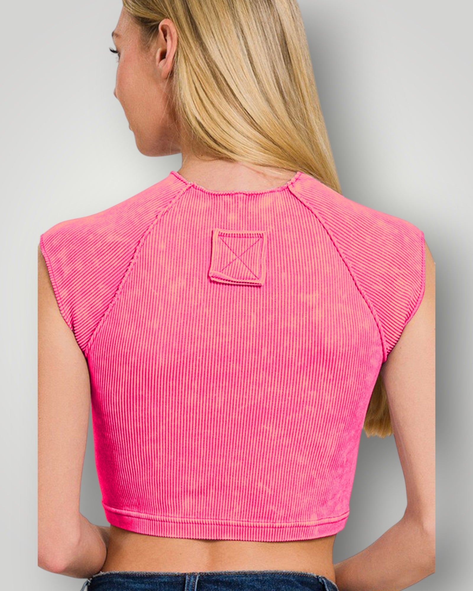 Person wearing a pink sleeveless top with a subtle pattern on a plain background