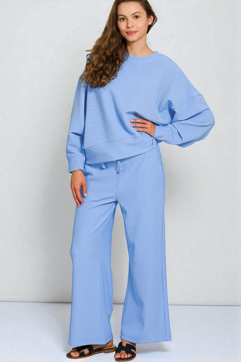 Woman wearing a light blue outfit with wide-leg pants on a white background