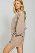 Woman wearing a beige outfit with a plain background