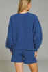 Person wearing a blue sweatshirt and shorts set against a gray background