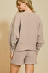 Woman wearing a beige sweatshirt and shorts set against a beige background