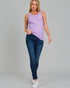 Woman wearing a purple sleeveless top and blue jeans on a gray background