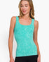 A woman wearing a turquoise ribbed scoop-neck tank top with a subtle white textured pattern, paired with black pants, against a plain white background.