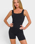 Woman wearing a black bodysuit against a plain background