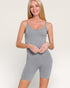 Woman wearing a gray bodysuit against a plain background