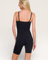 Person wearing a black bodysuit against a plain background