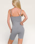 Person wearing a gray bodysuit against a plain background