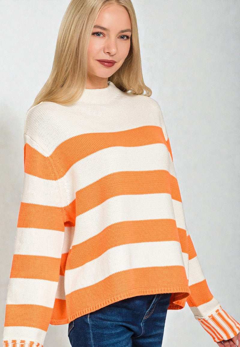 Woman wearing a white and orange striped sweater on a plain background