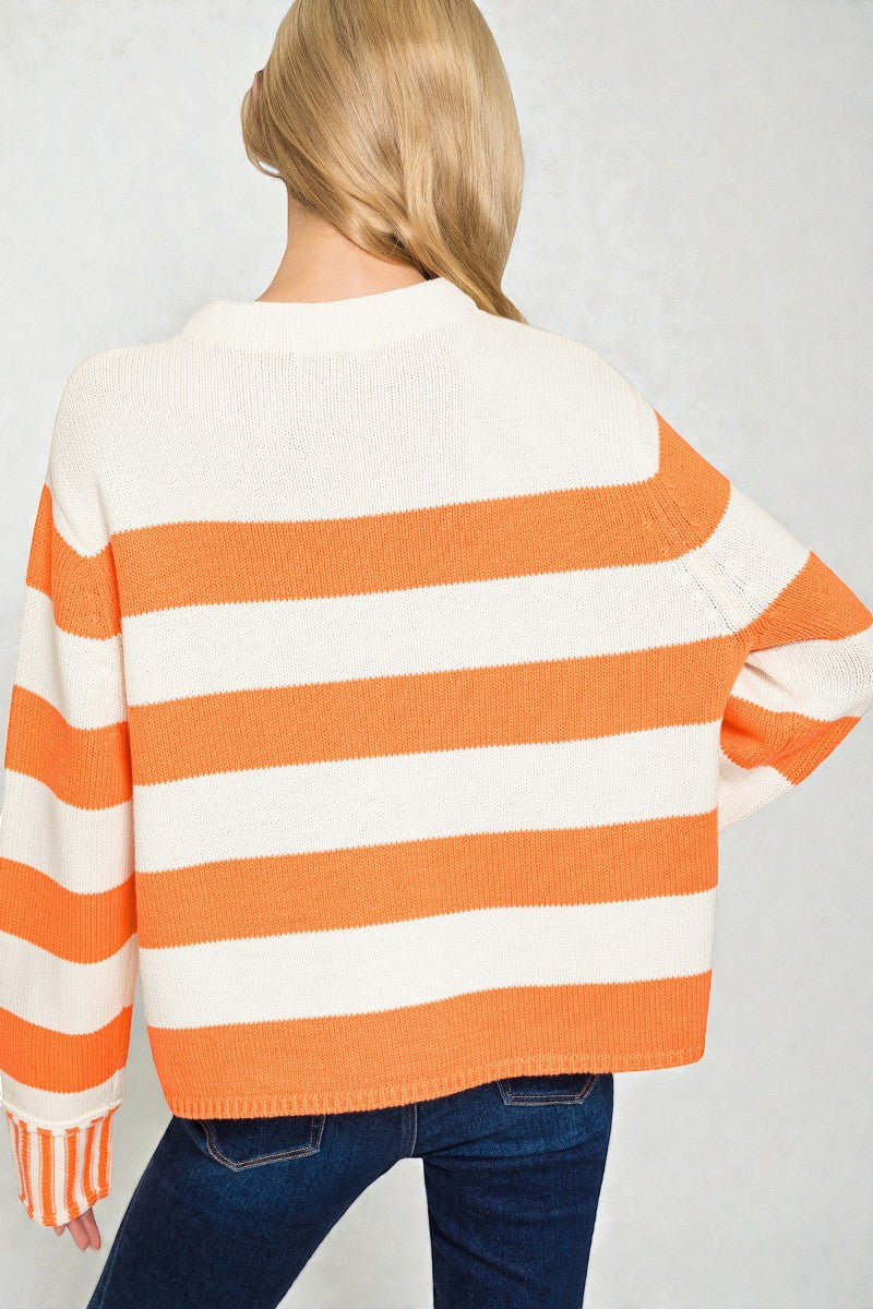 Person wearing an orange and white striped sweater on a plain background