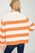 Person wearing an orange and white striped sweater on a plain background