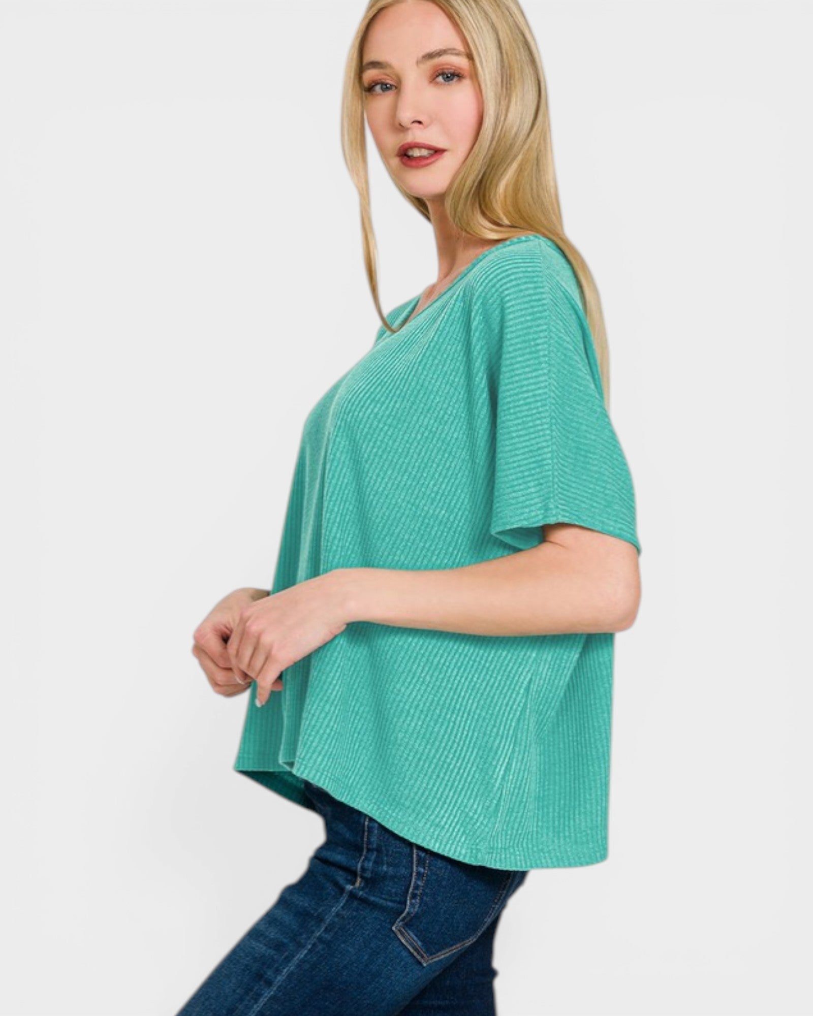 Woman wearing a teal sweater and blue jeans on a white background