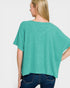Woman wearing a teal ribbed top and blue jeans on a white background