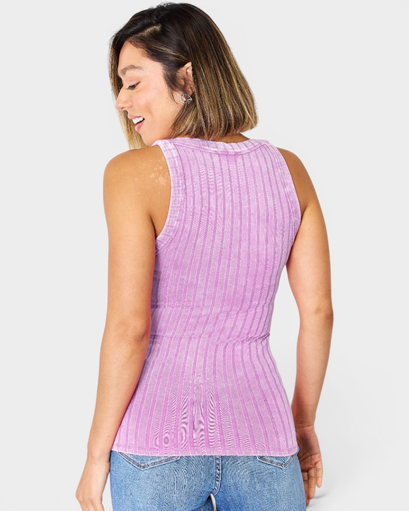 Woman wearing a purple ribbed tank top against a white background