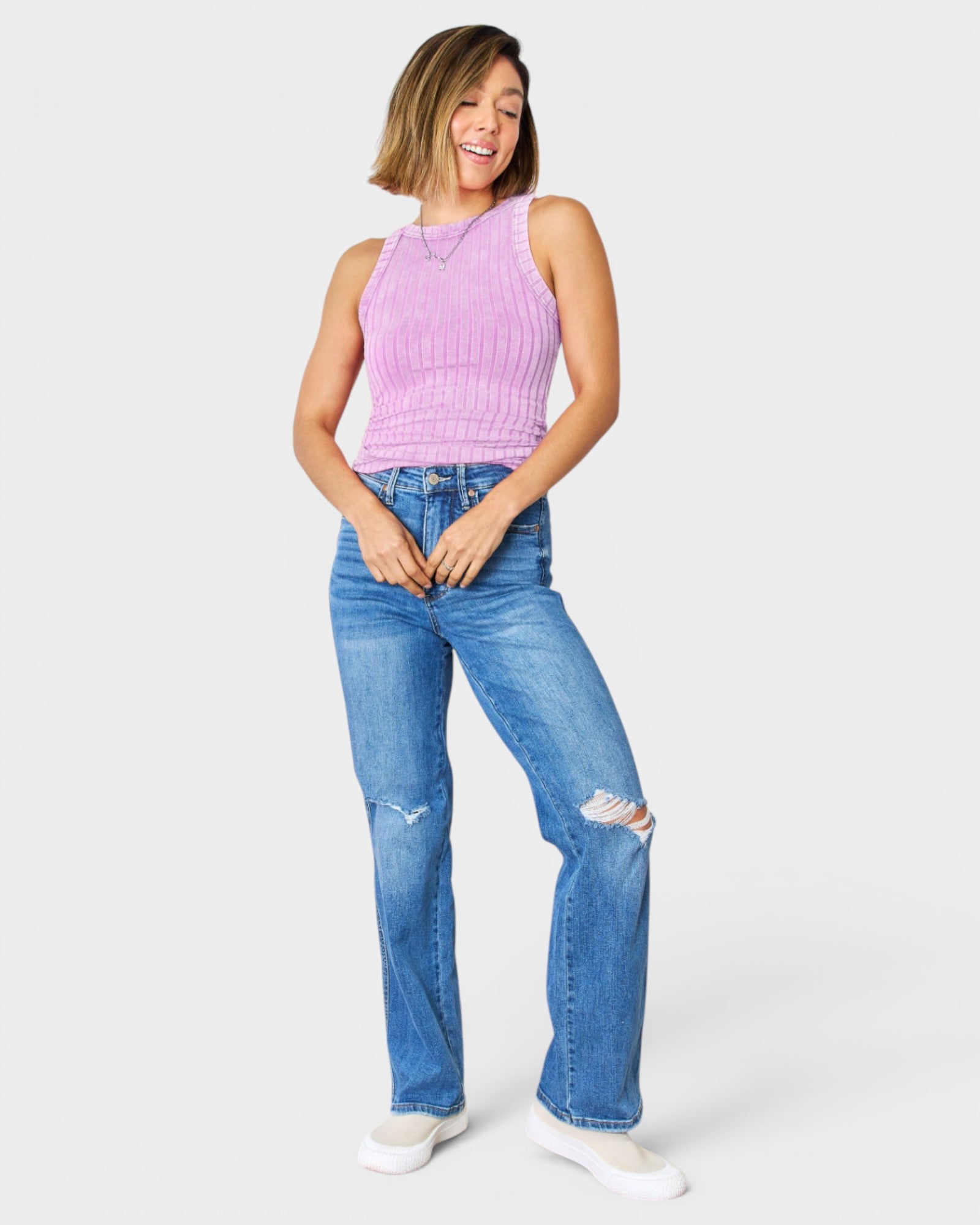 Woman wearing a pink sleeveless top and blue jeans on a white background