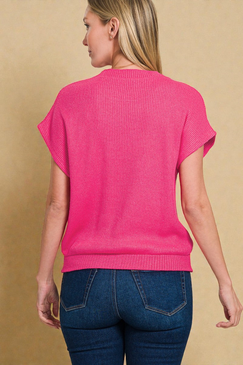 Woman wearing a bright pink sweater and blue jeans on a beige background