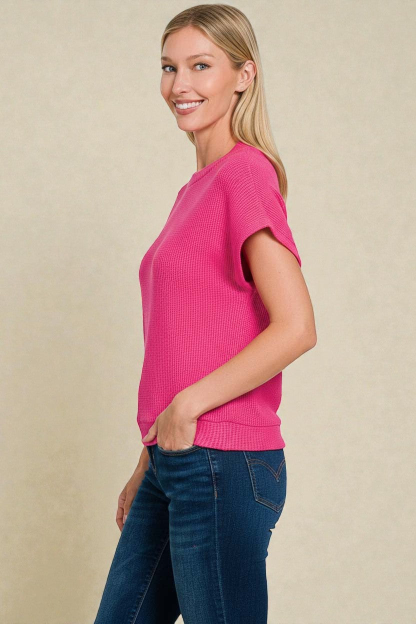 Woman wearing a pink sweater and blue jeans against a beige background