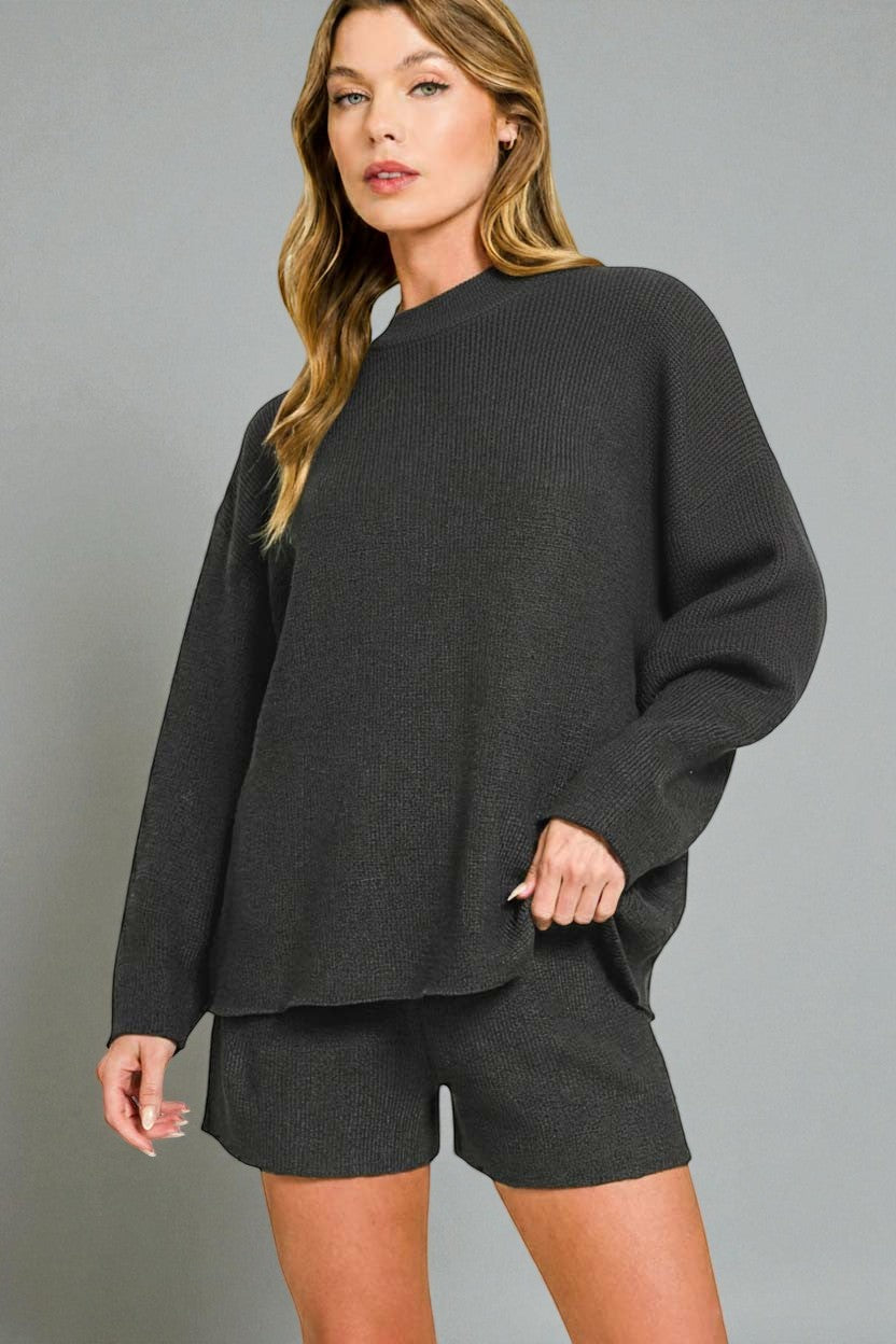 Woman wearing a dark gray sweater and shorts on a gray background