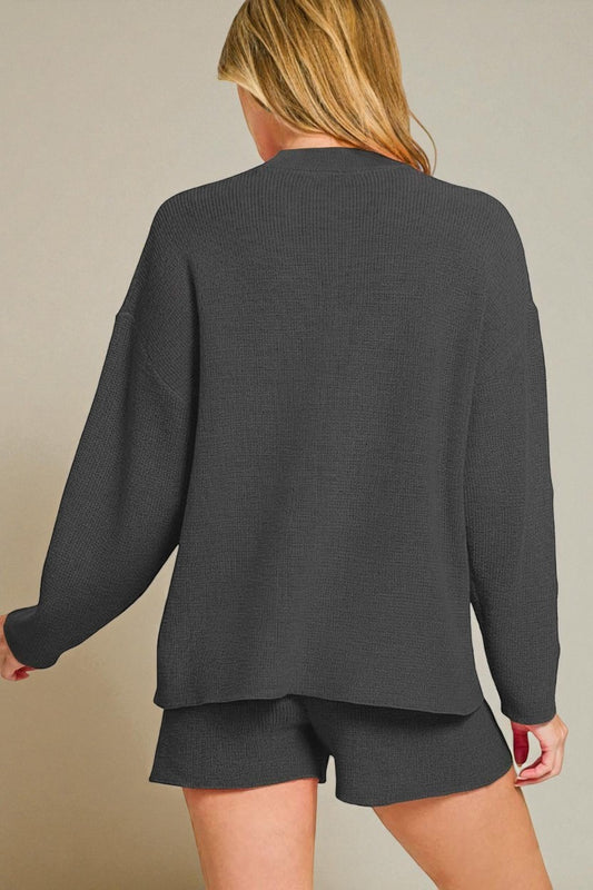 Person wearing a dark gray sweater and shorts on a beige background