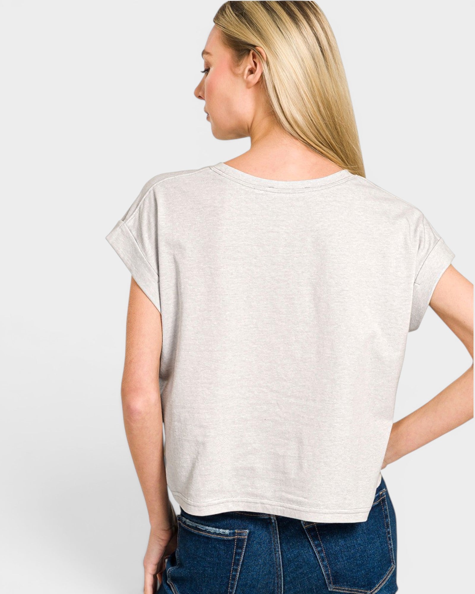 Woman wearing a light gray t-shirt and blue jeans on a white background