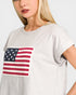 Person wearing a gray t-shirt with an American flag design on a plain background