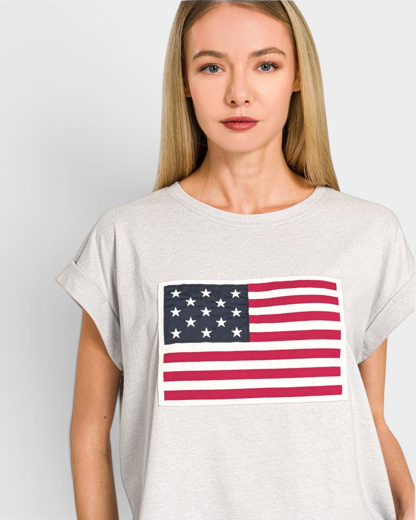 Woman wearing a white t-shirt with an American flag design on a plain background