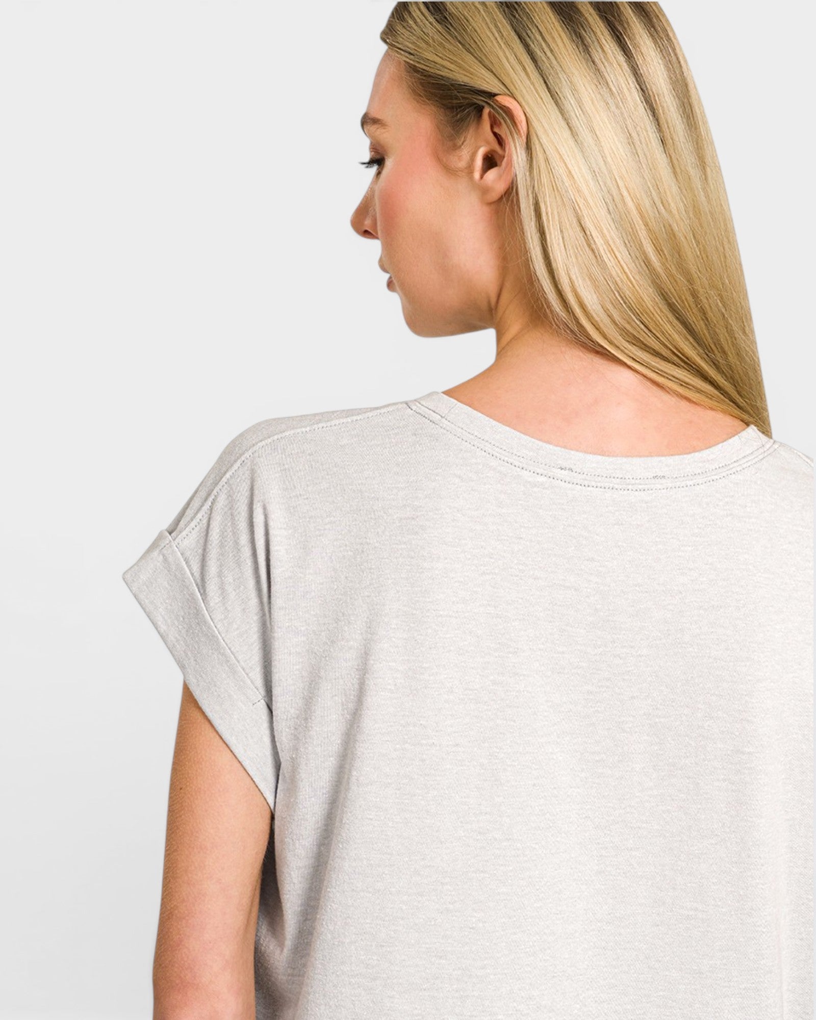 Woman wearing a light gray t-shirt against a plain background