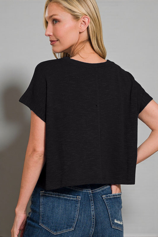 Woman wearing a black t-shirt and blue jeans against a gray background