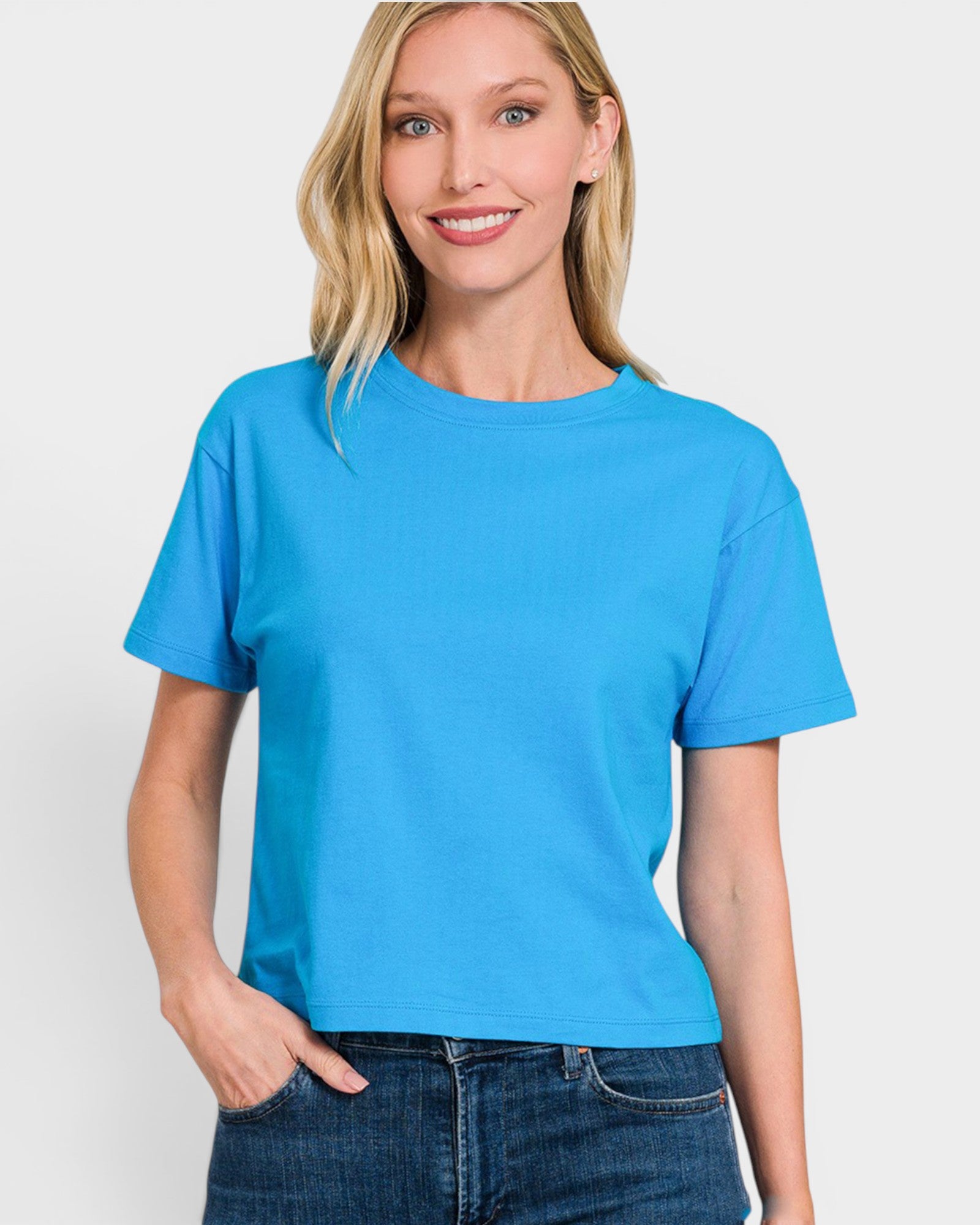 A woman wearing a bright blue short-sleeve t-shirt, against a plain light gray studio background.