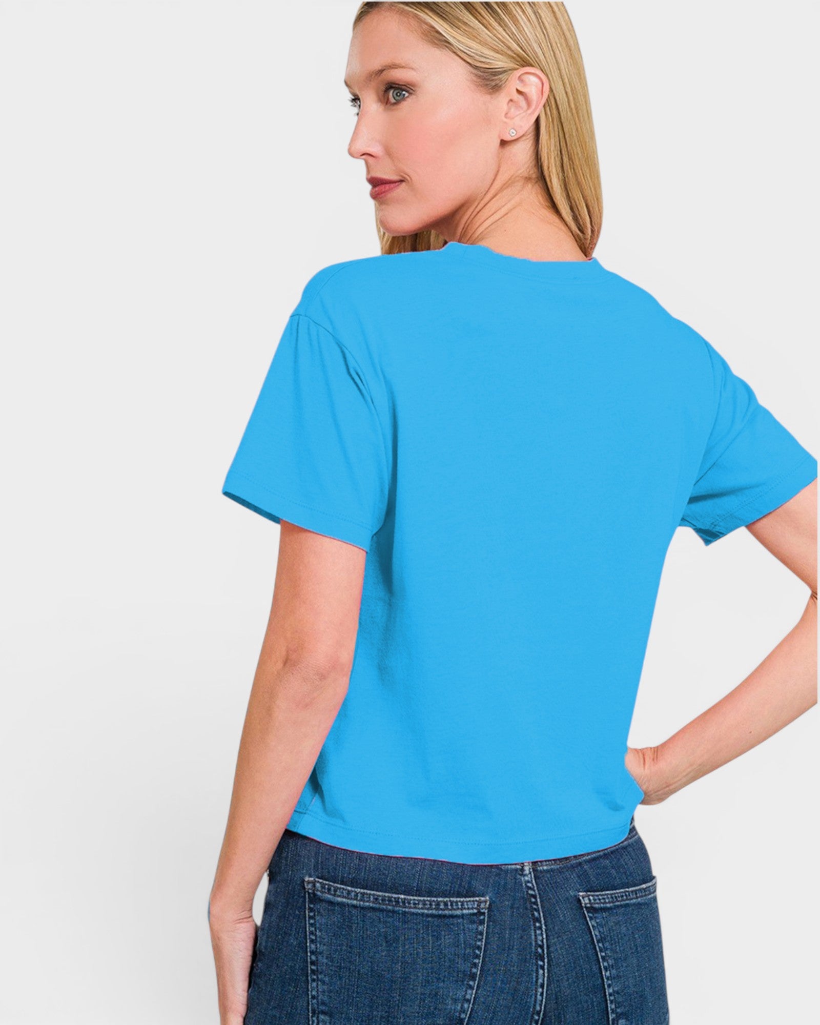 A woman wearing a bright blue short-sleeve t-shirt, shown from the back against a plain light gray studio background.