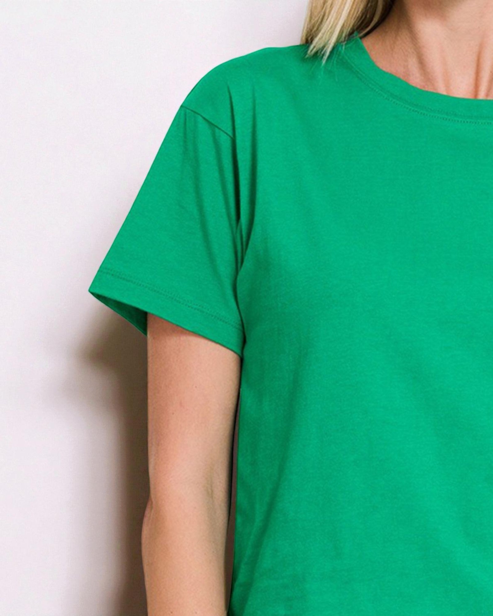 Green t-shirt worn by a person against a plain background