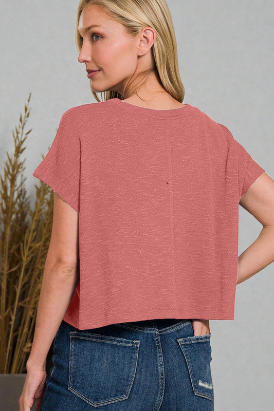 Woman wearing a pink top and blue jeans against a gray background