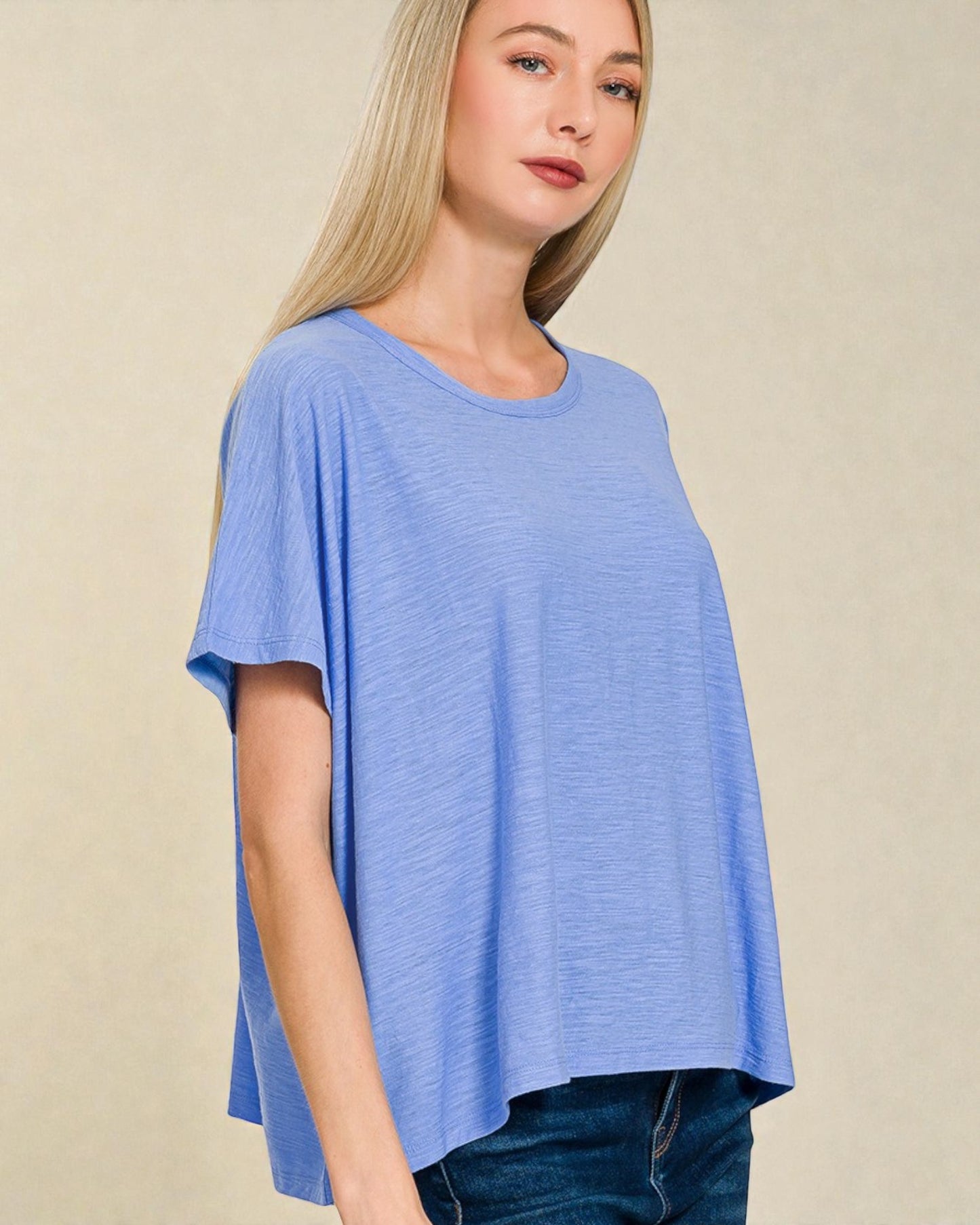 Woman wearing a blue oversized t-shirt against a beige background