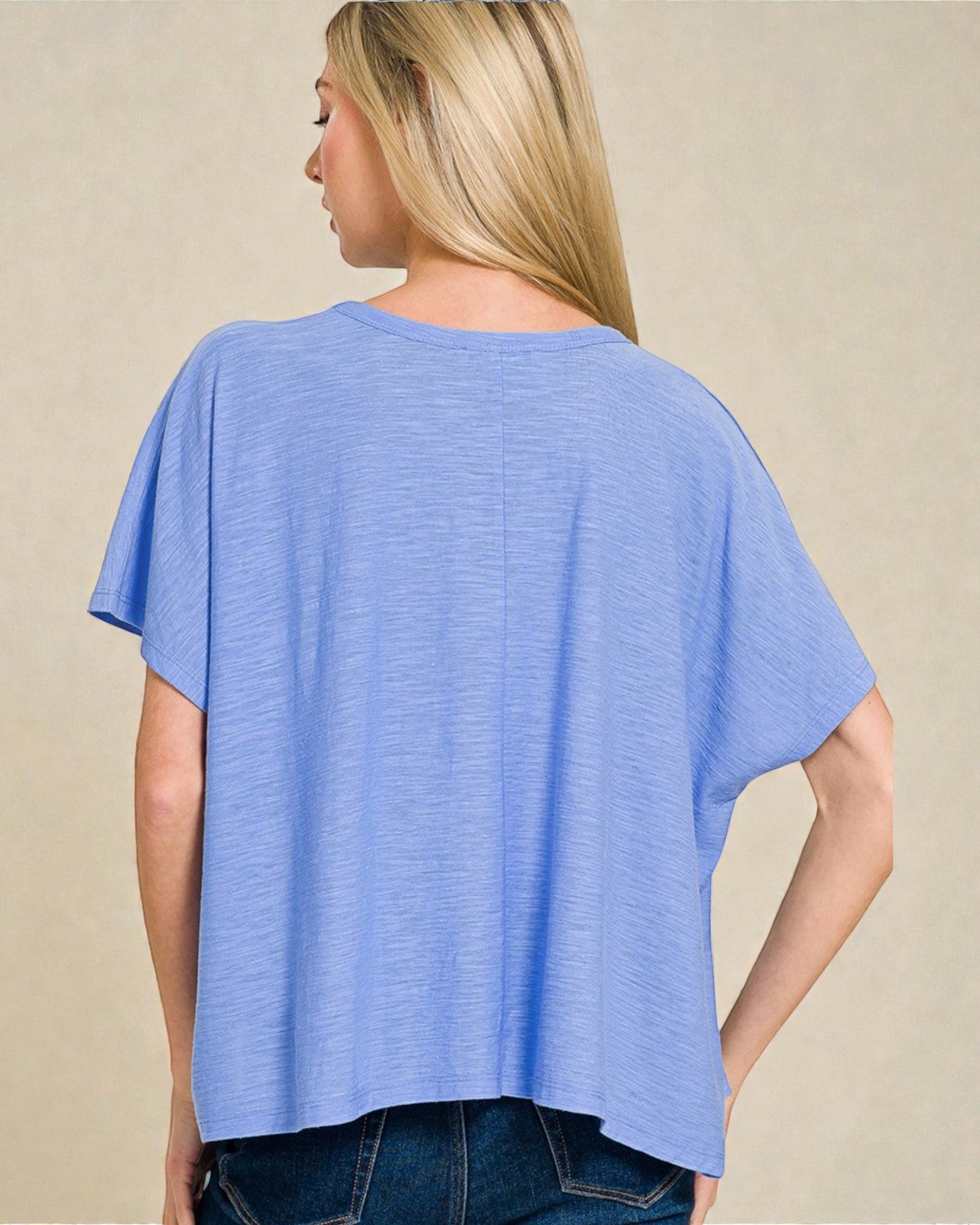 Woman wearing a blue oversized t-shirt against a beige background