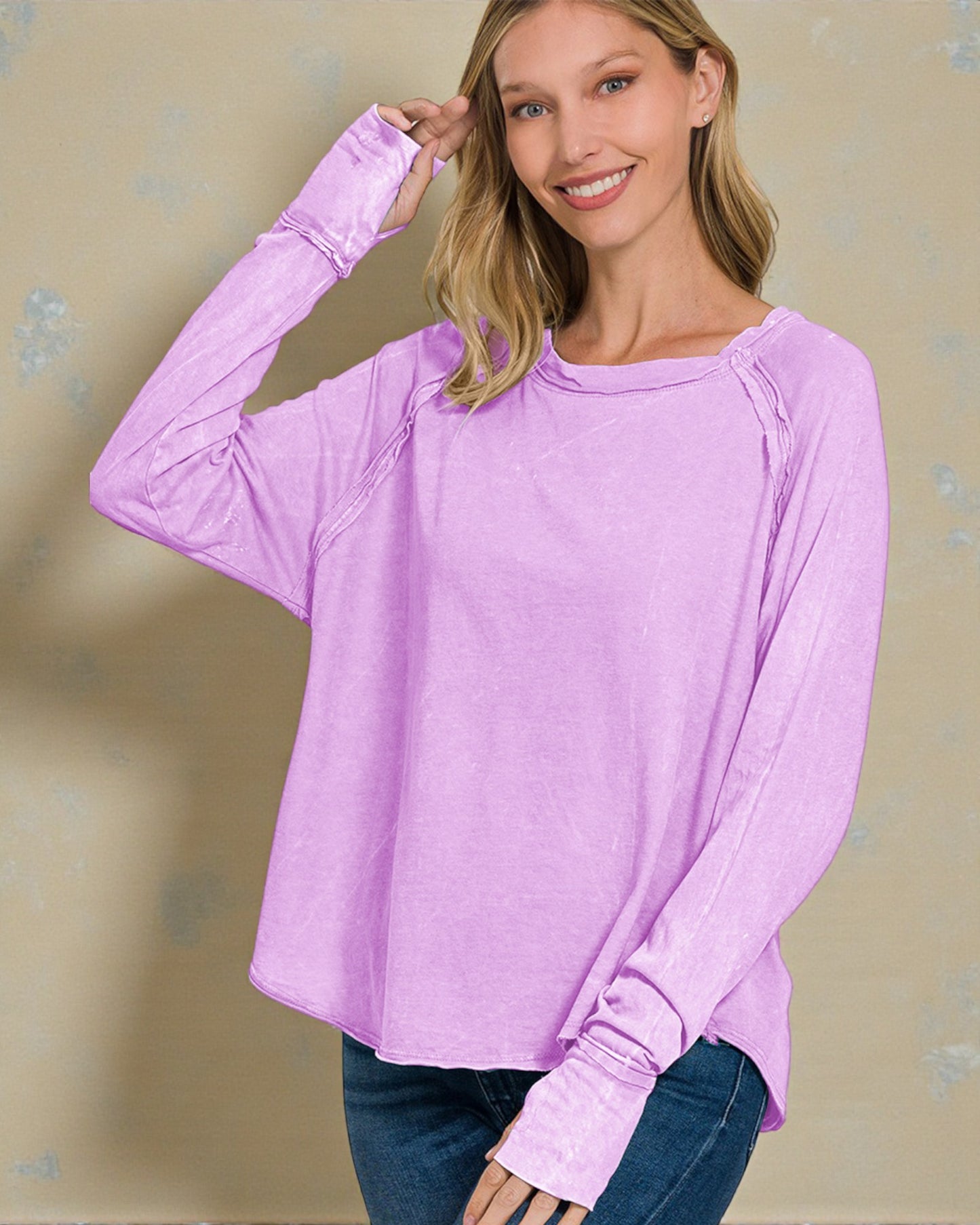 Woman wearing a light purple long-sleeve top against a beige background