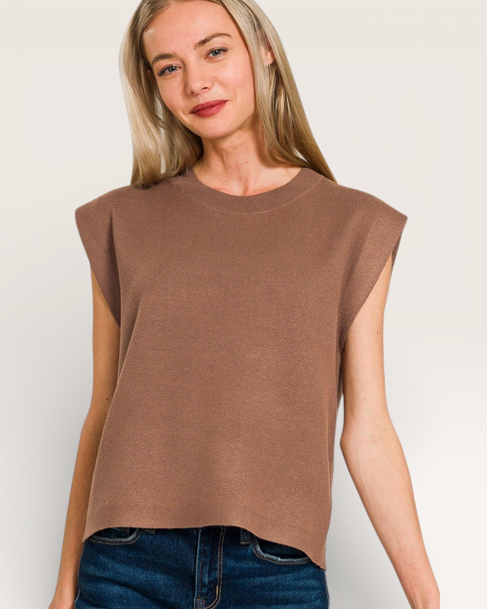 Woman wearing a brown sleeveless top against a plain background