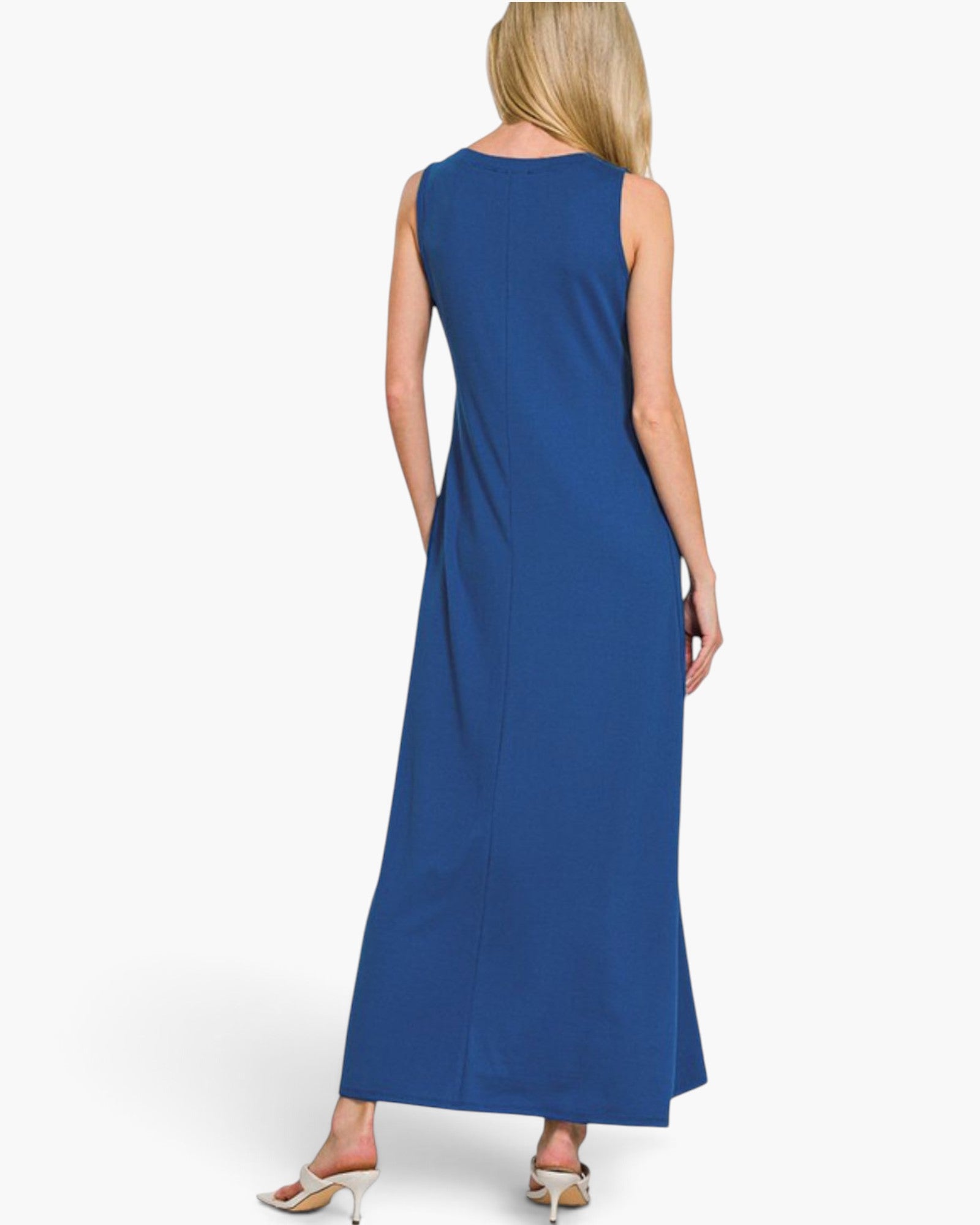 A woman shown from the back wearing a sleeveless, floor-length royal blue dress against a plain light gray studio background.