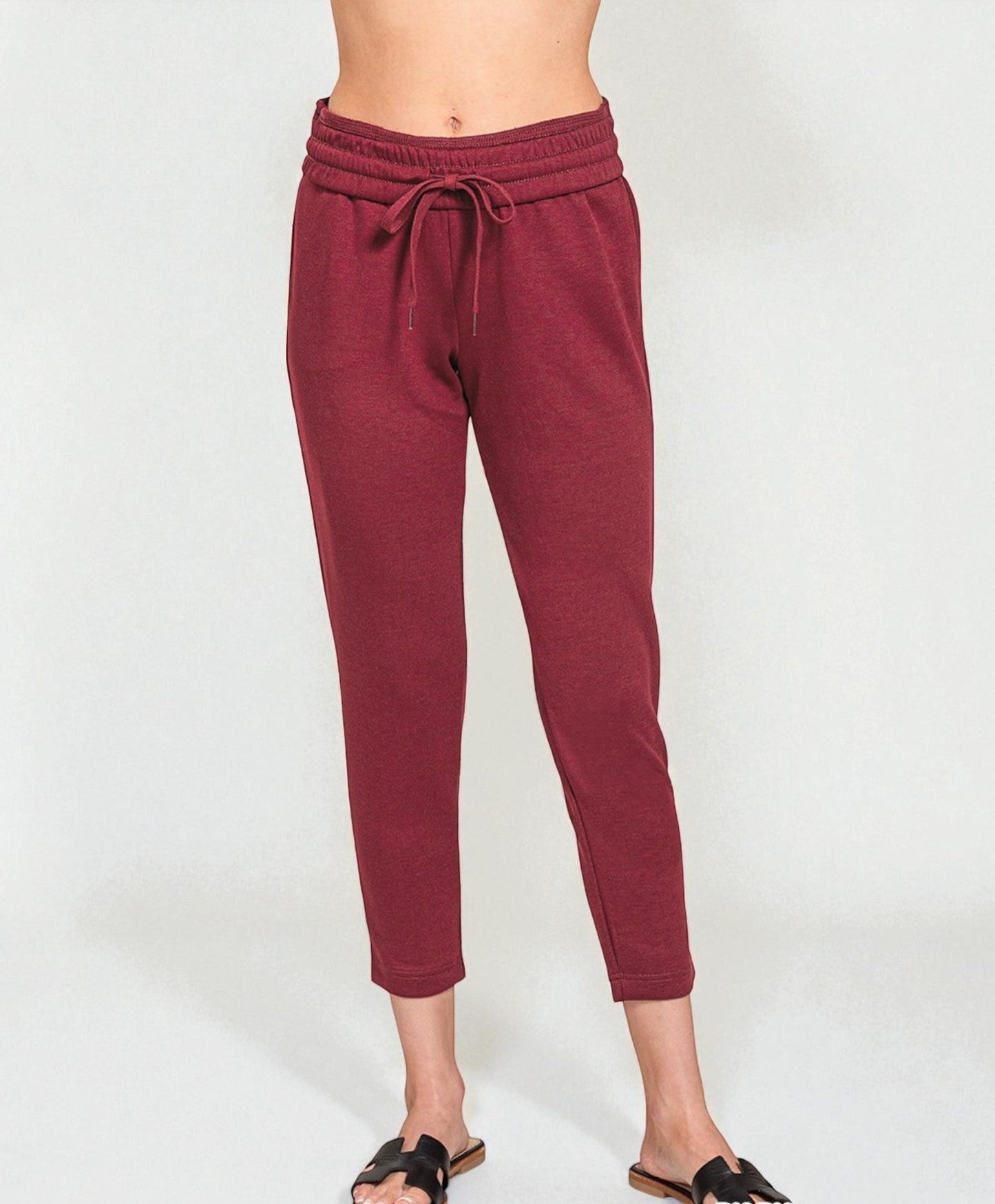 Maroon jogger pants worn by a person on a white background
