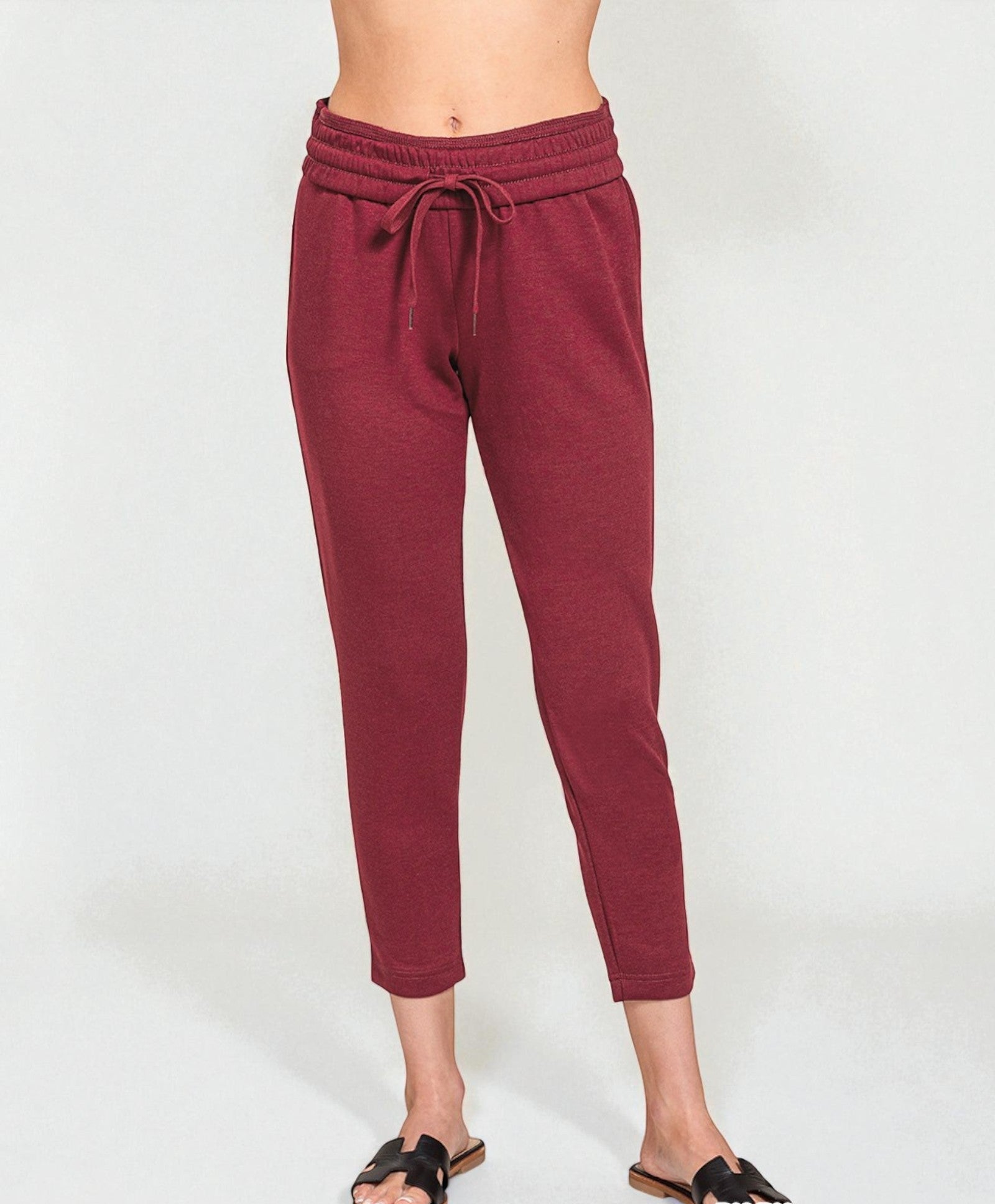 Maroon jogger pants worn by a person on a white background