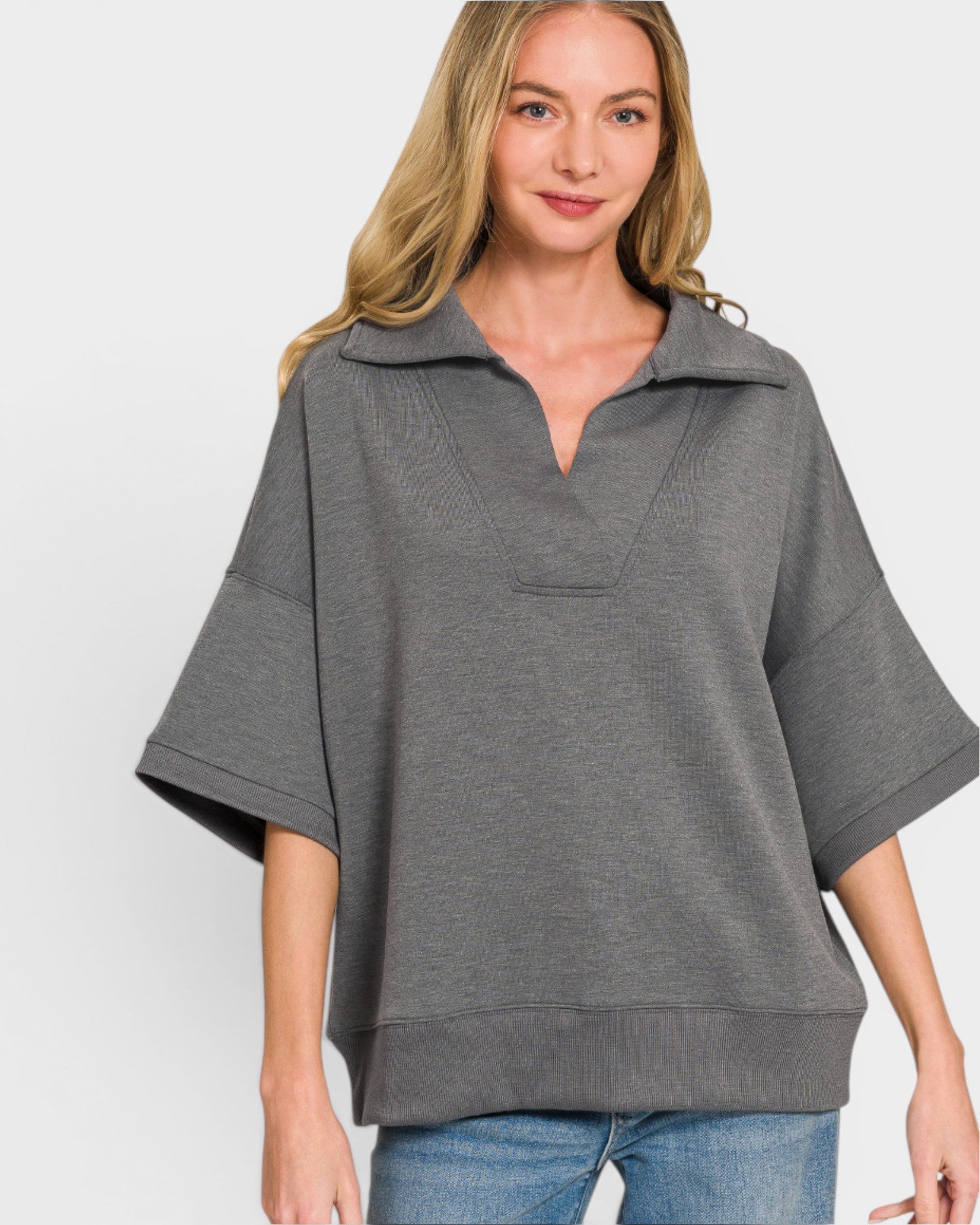 Woman wearing a gray poncho over a white background