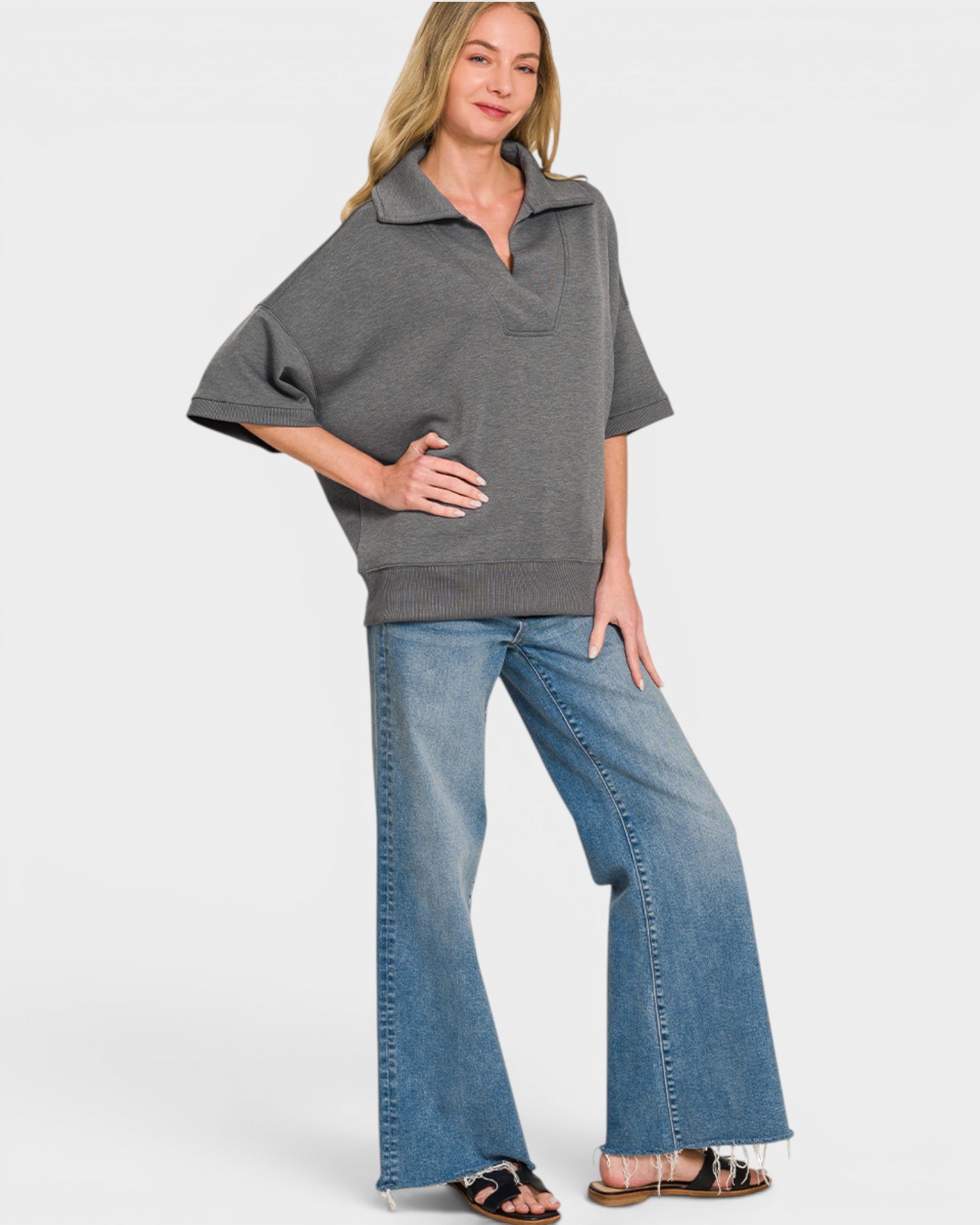 Woman wearing a gray poncho and blue jeans on a white background
