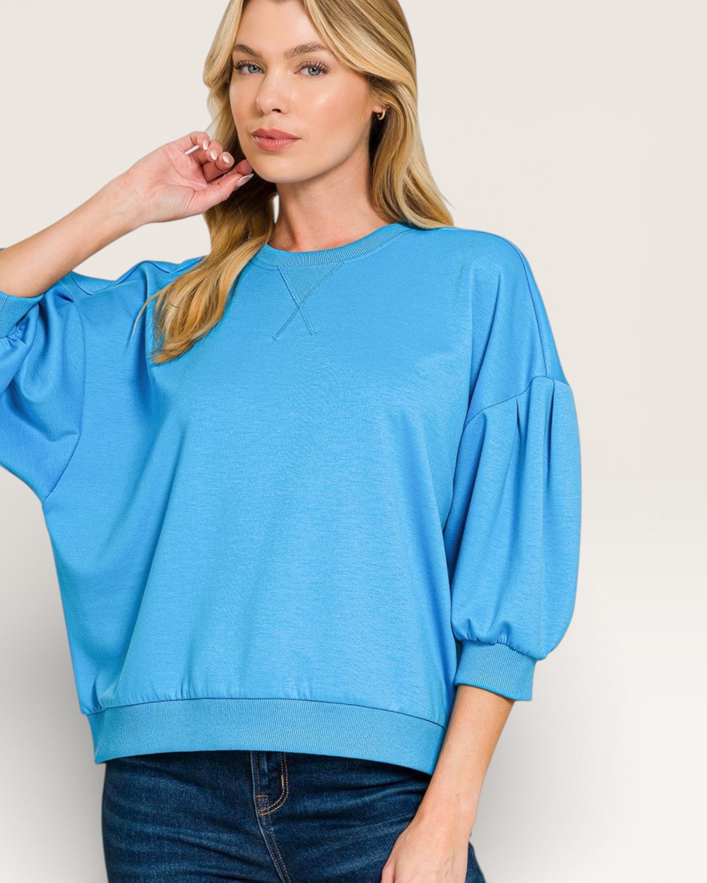 Woman wearing a blue sweater with puffed sleeves on a white background